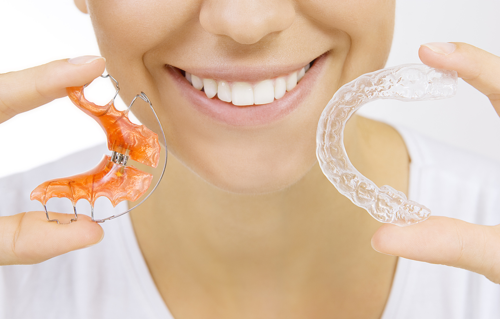 Beautiful smiling girl holding retainer for teeth (dental braces) and individual tooth tray